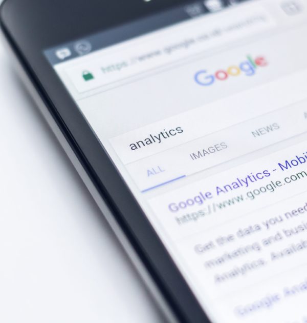 Picture of a phone with a Google search for "Analytics" on it, representing search advertising analytics